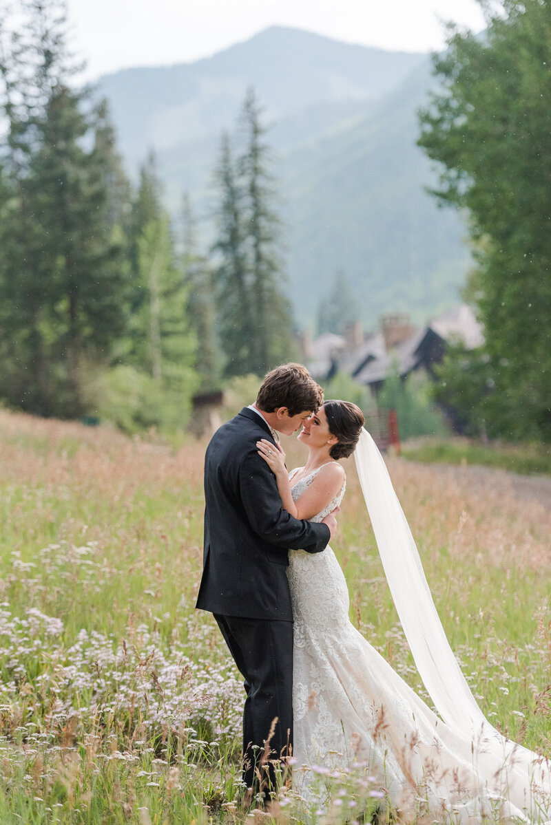 Wedding Photographer,  a bride and groom lean in for kiss in mountain meadow