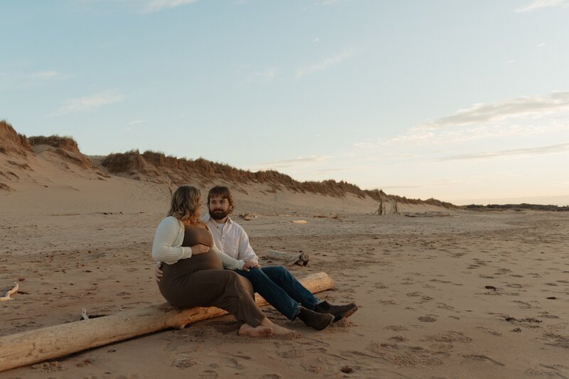 couple sitting on beach for lifestyle photos in pei