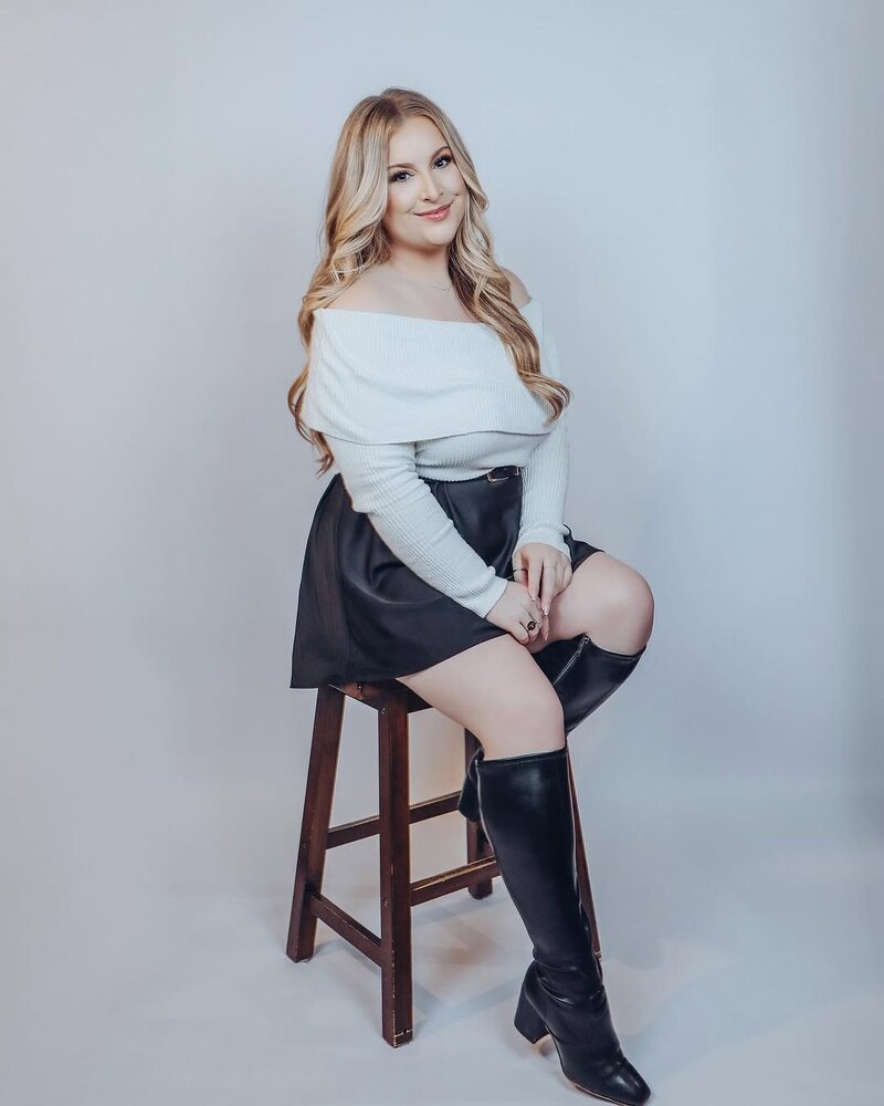 Woman sitting in a chair leaning to one side with her legs crossed.
