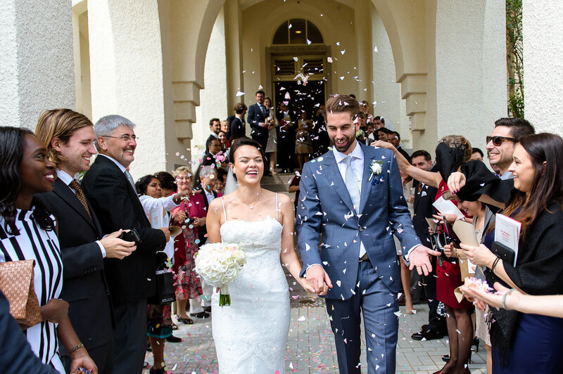 bride and groom walk out from aisle after ceremony with friends throw confetti