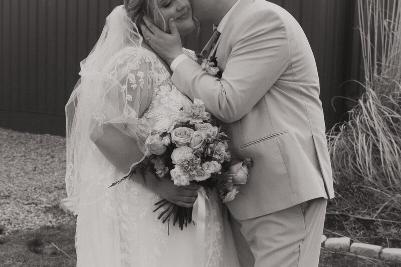 Wedding session couple kisses with bouquet