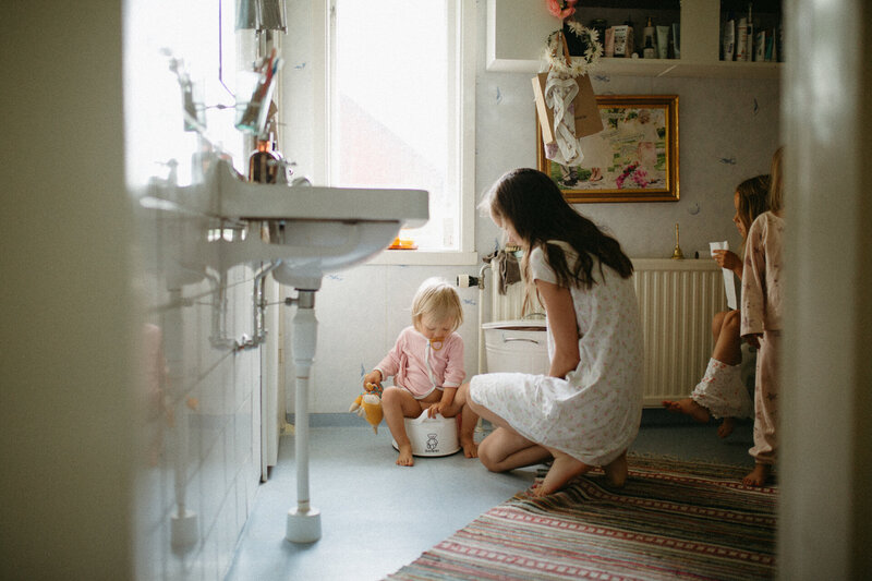 En mamma hjälper sina barn med morgonrutinerna på toaletten under en familjefotografering