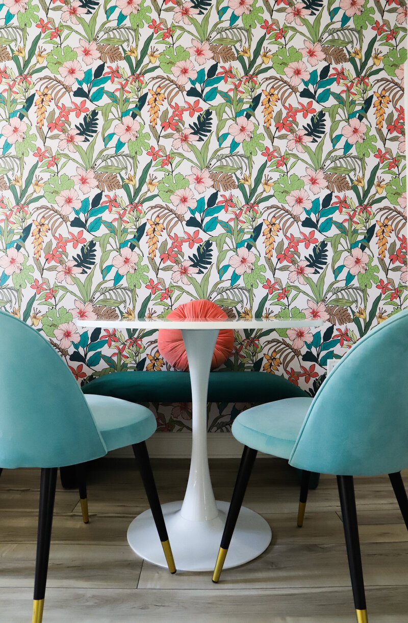 dining room with floral wallpaper and blue accent chairs