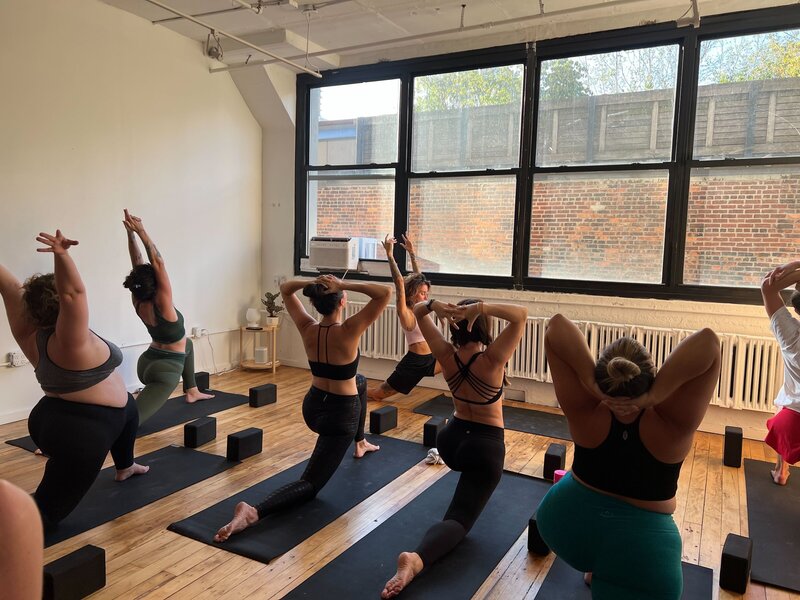 Several women in a yoga pose during class at Held Space