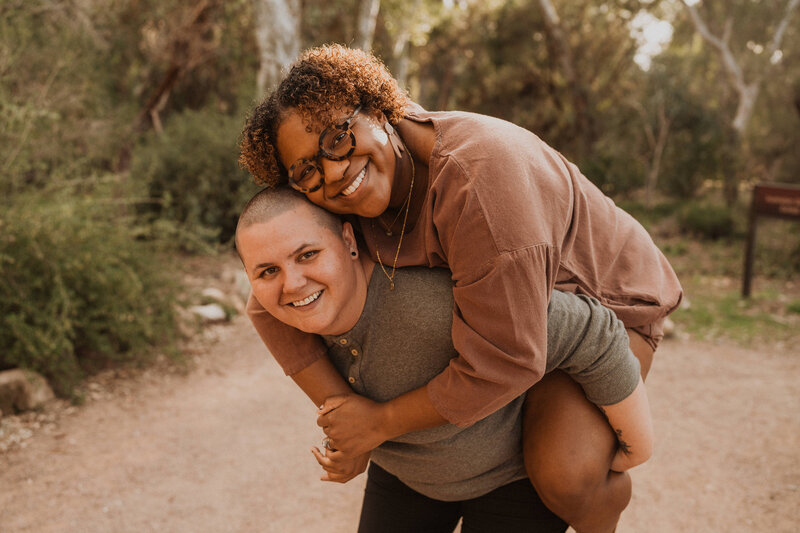 Partners with their arms around each other as they smile.