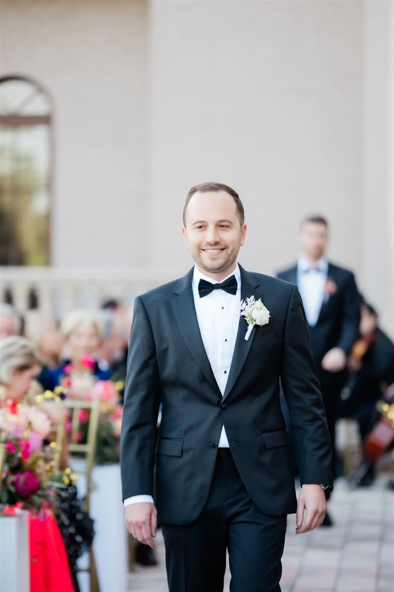 The groom walking down the aisle at his wedding ceremony at the country club of Orlando.