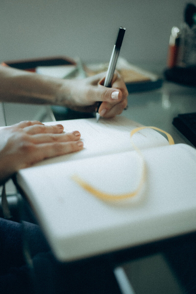 Andrea's hand writing on her notebook using a pen