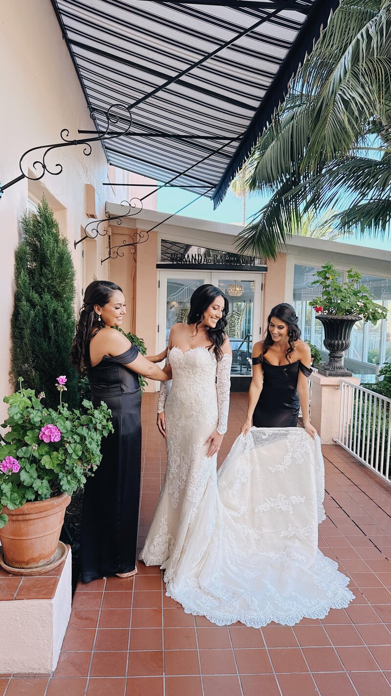Maids of Honor and sisters helping the bride adjust her wedding gown on the balcony of La Valencia.
