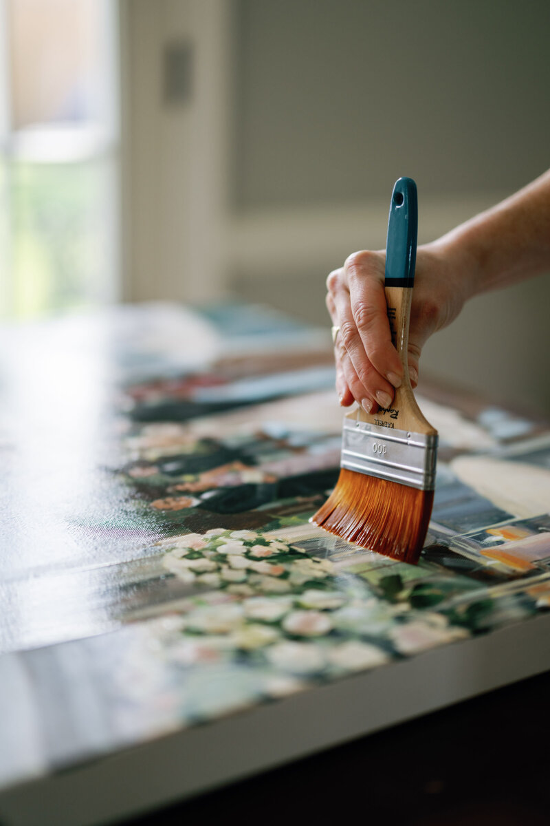 Stephanie Gaffney paints varnish on large live wedding painting in her New Orleans studio