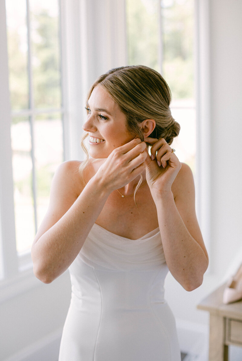 Bride putting on earrings