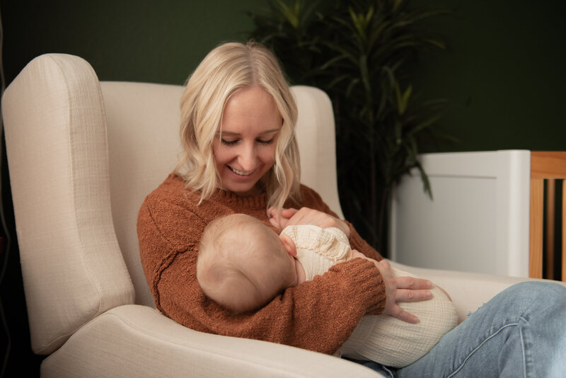 mother smiling down at her baby as she feeds