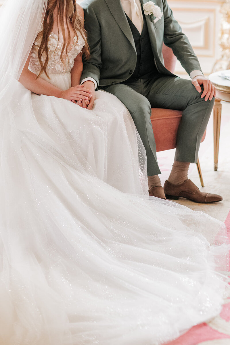 Bruid en bruidegom delen een moment op een trouwbankje tijdens hun ceremonie, perfect gepland door een weddingplanner.