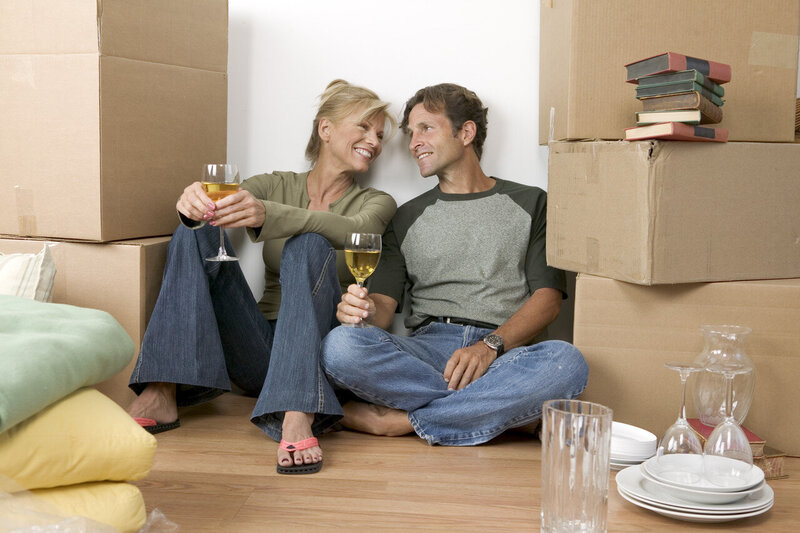 New homeowners drink wine in their new home surrounded by boxes