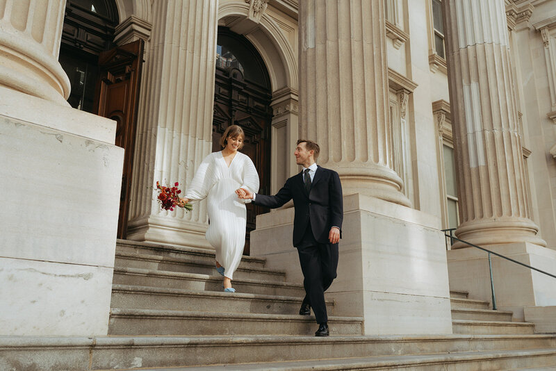 bride and groom walking on city hall after NYC elopement shot by Elsie Goodman Photography | NYC Elopement Packages