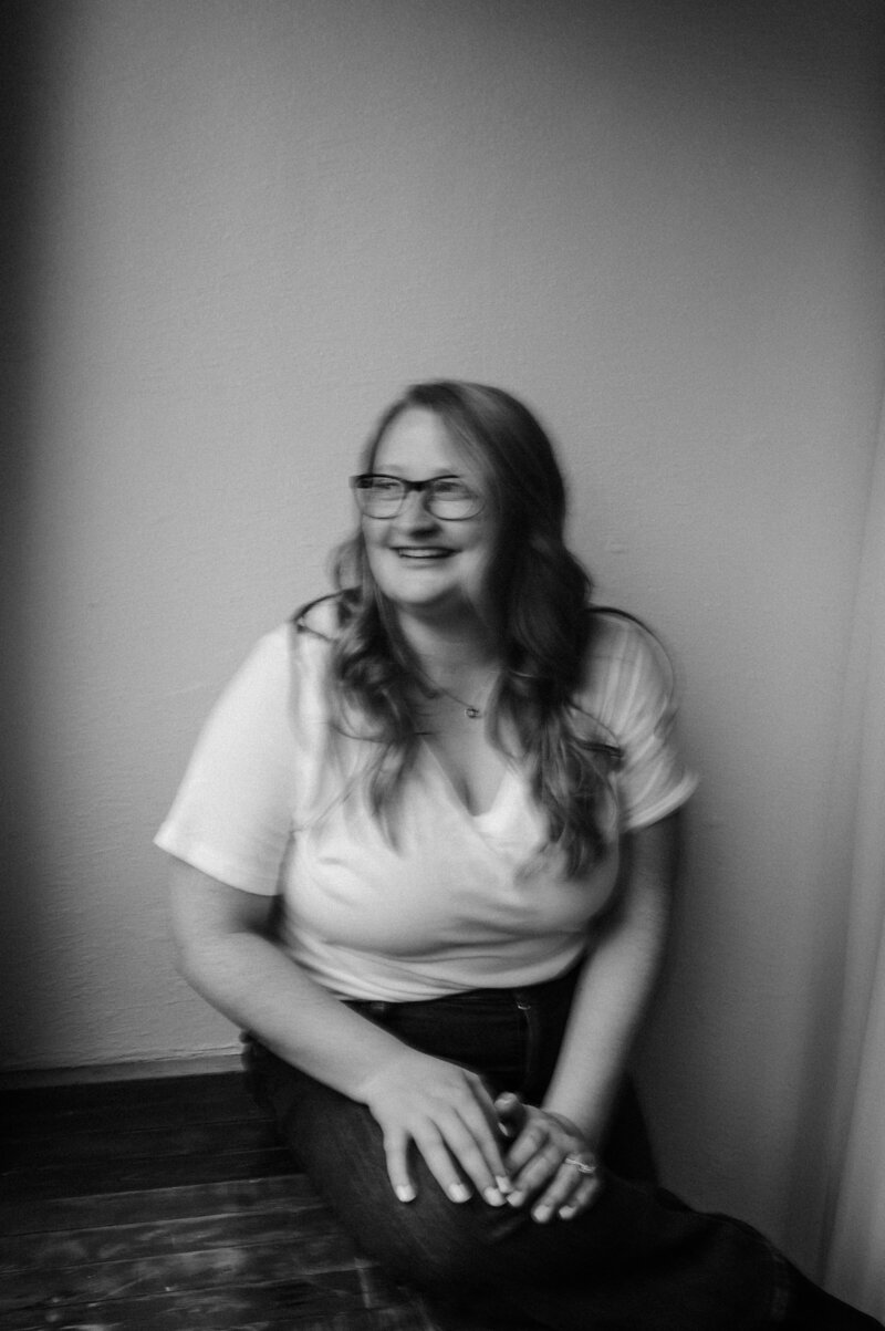 Black and white image of women smiling, wearing glasses dressed professionally. 