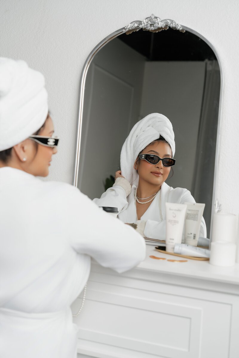 Bianca looking in mirror smiling with bathrobe and towel on