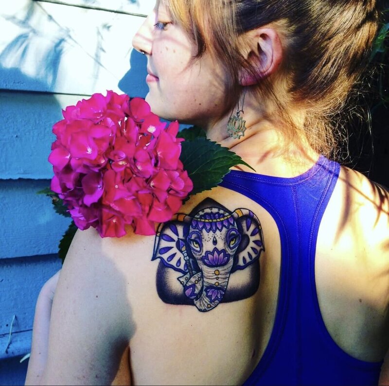 woman with blue elephant tattoo holding  a pink flower