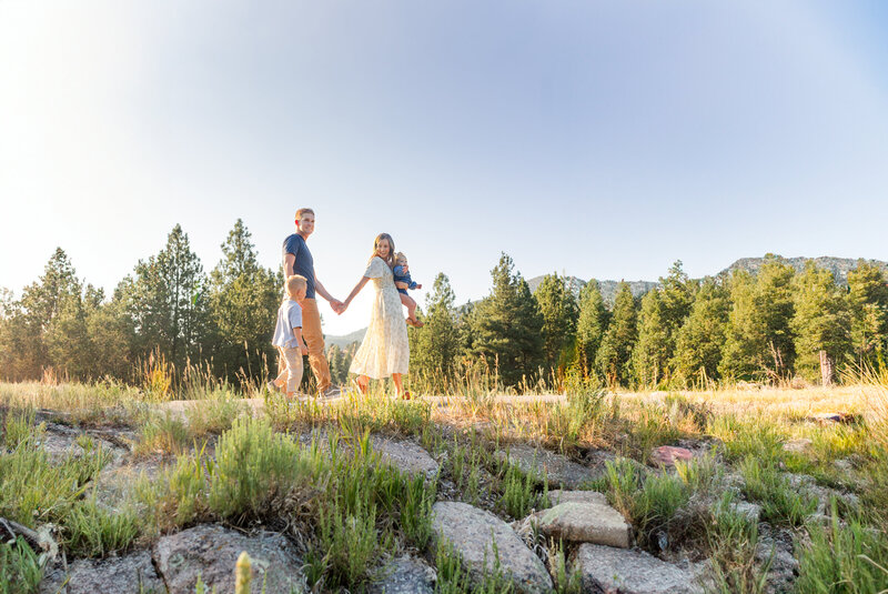 mom and dad holding toddlers hands at sand hollow state park as they walk in the red sand