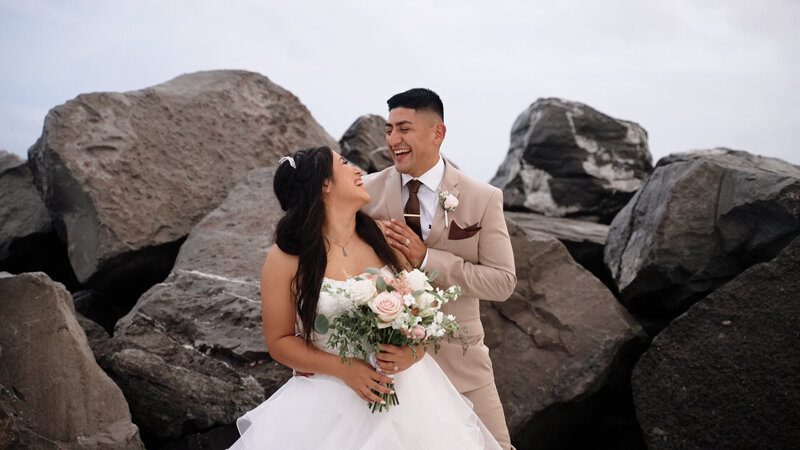 Couple laughing in front of rocks for a Florida beach wedding.