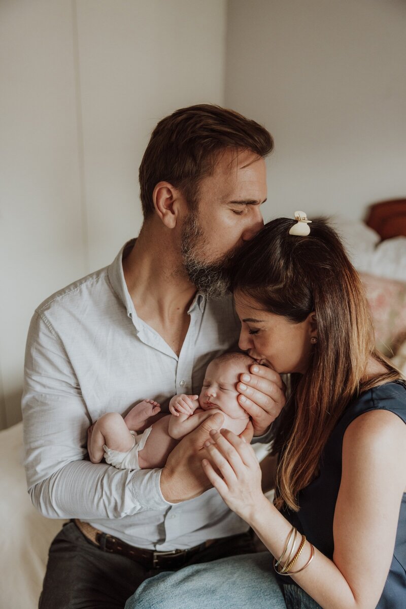 Parents holding and kissing newborn baby