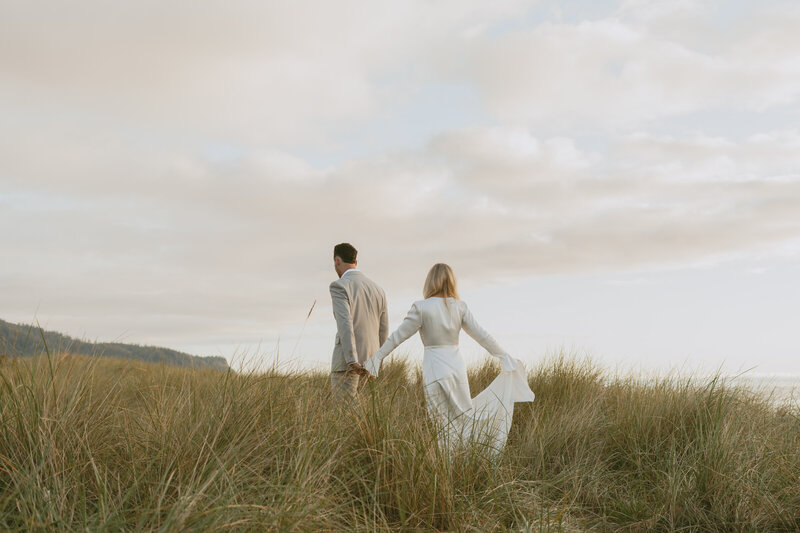 groom running through grassy field toward bride