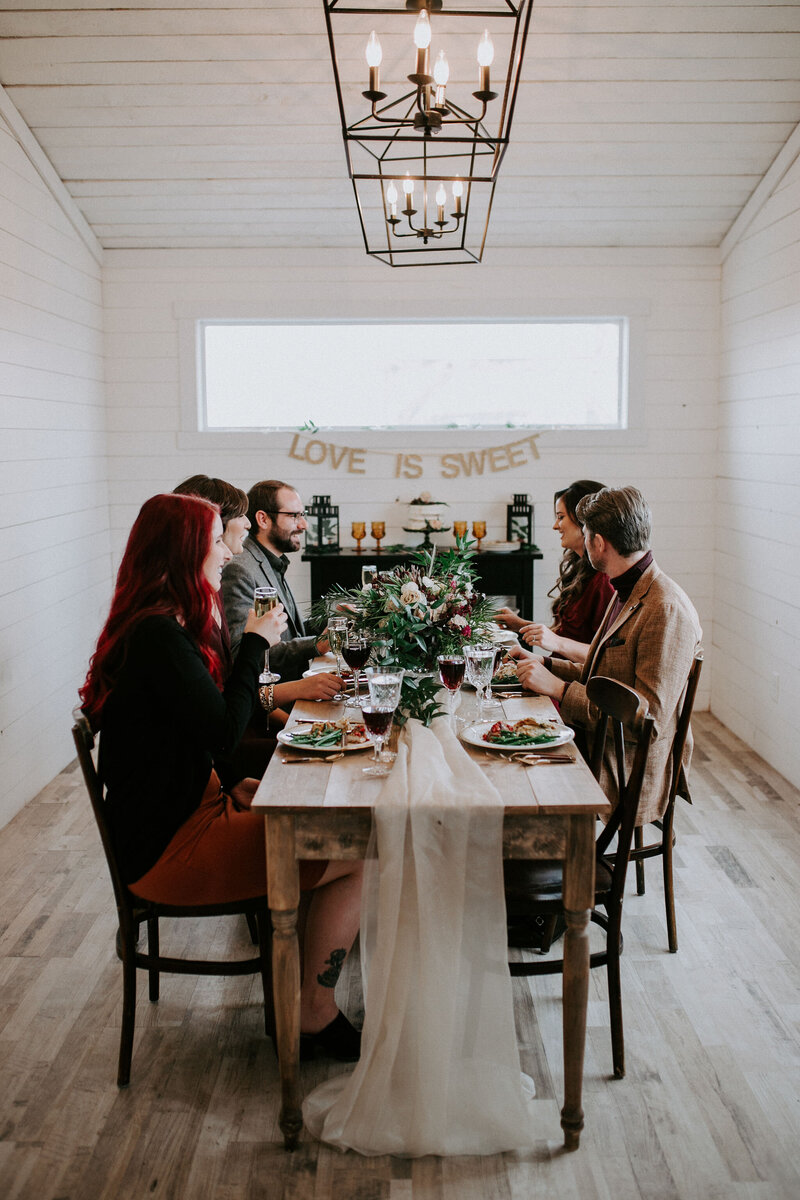 guests sitting at a wood table in a white room