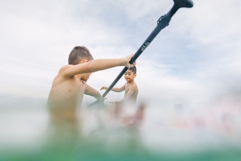 Two boys paddle in the ocean in Waikiki.