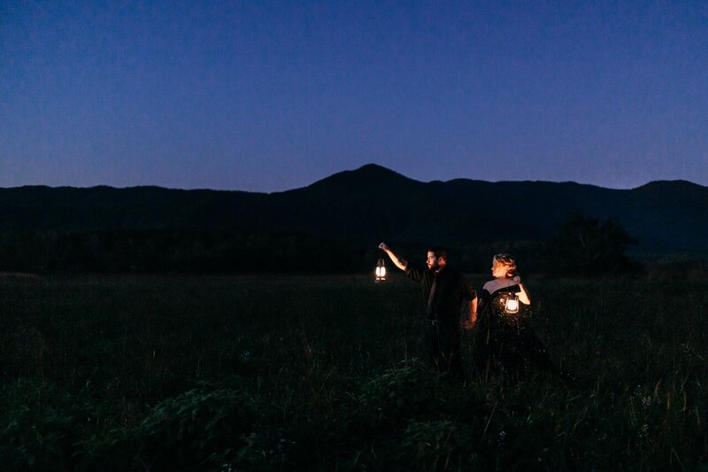 Eloping couple walk with lanterns amoung mountains in dark setting