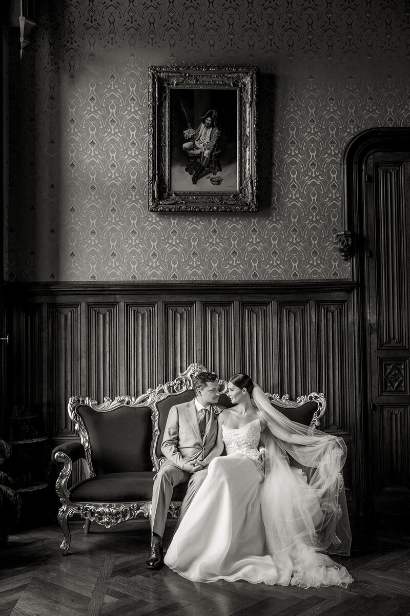 Bride and groom sharing a romantic moment at Château Challain with soft light streaming through the high windows, captured in elegant, natural wedding photography.