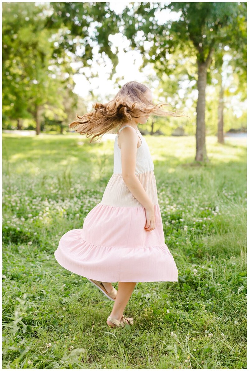 Family photographer tulsa - Caroline Eidson - captures golden hour family portrait of daughter spinning in field. 