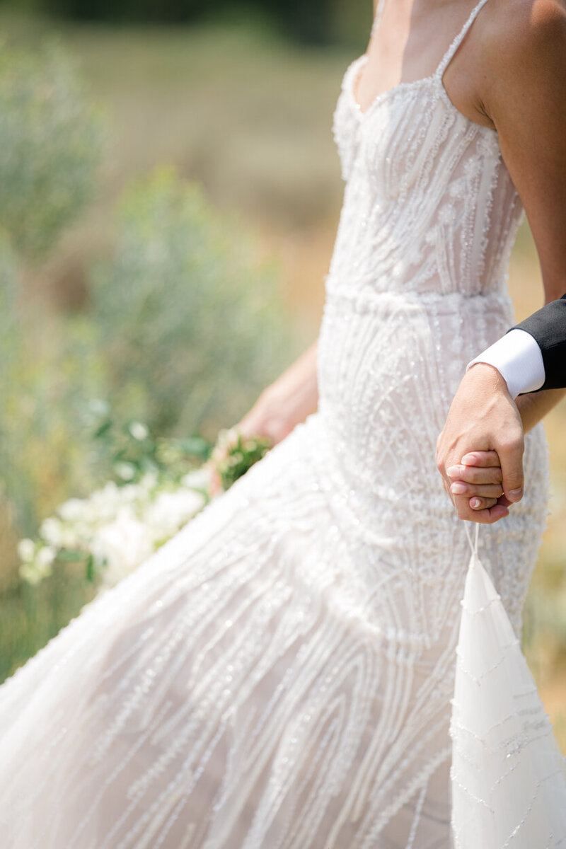 close up of bride and groom holding hands and bride's sparkly dress