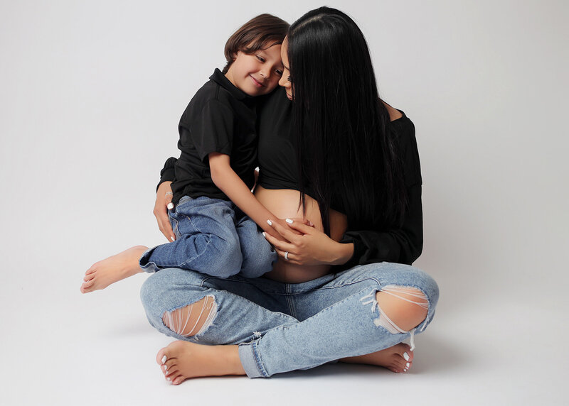 Mom and son posing on white background at mom's maternity photography session.