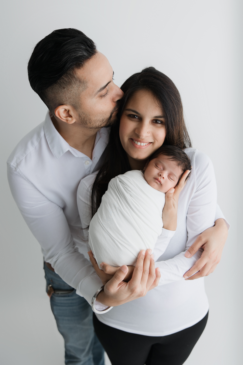 newborn-baby-with-mom-and-dad-kissing-mom-head