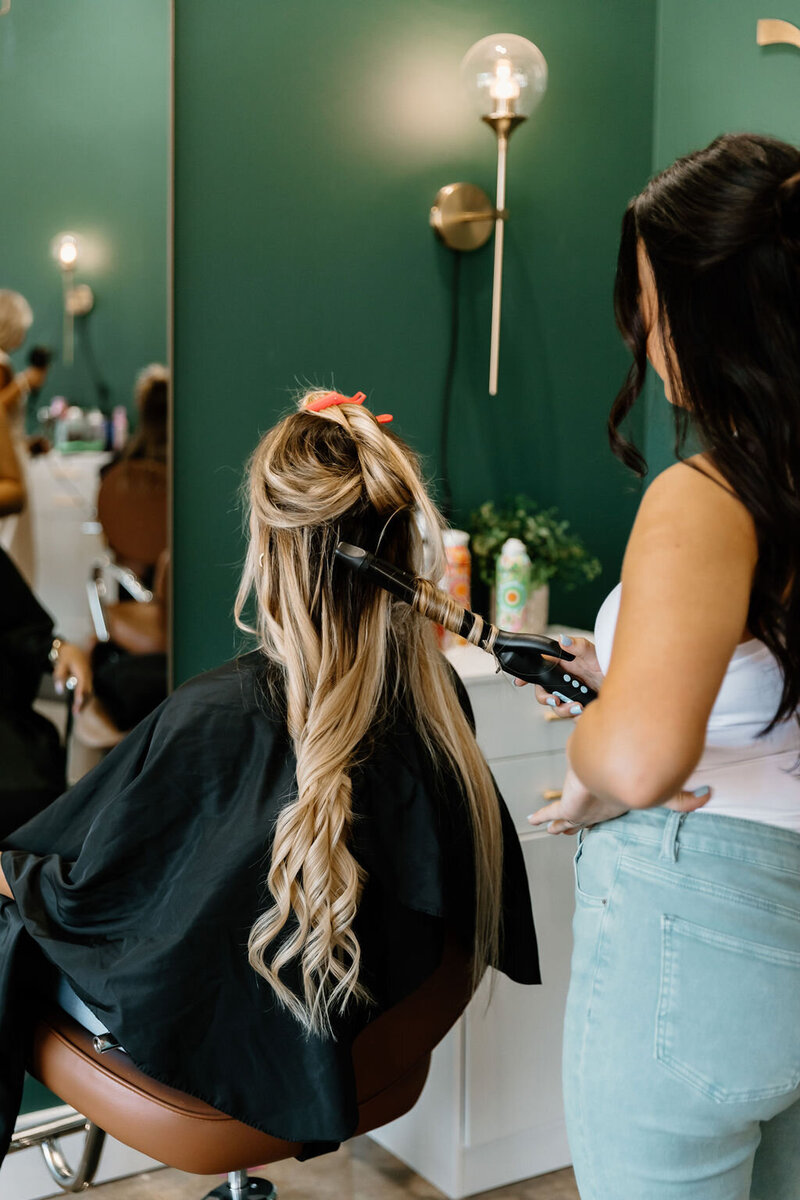 Professional hairstylist applying natural-looking hair extensions at The Vanity Hair Studio in Griffin, Georgia, adding length, volume, and fullness for a seamless finish.