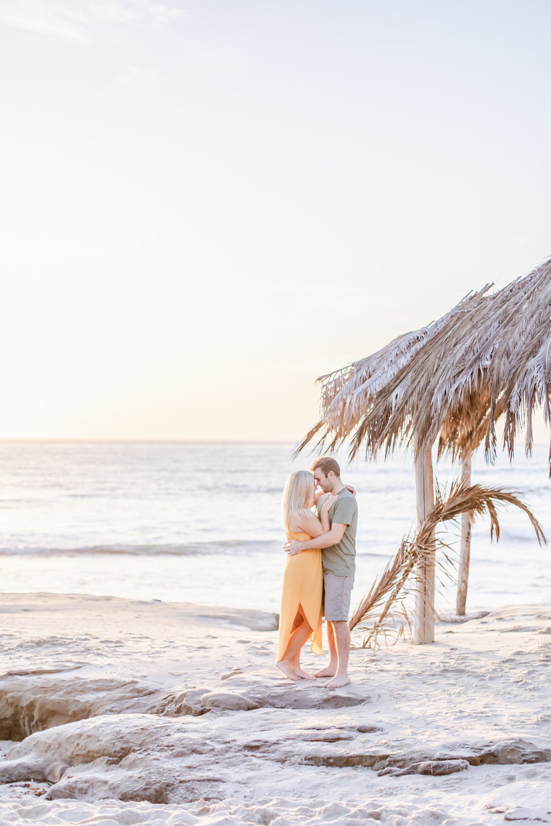 Couple on a rock by tiki in windansea beach for engagement session by san diego engagment photographer - Camila Margotta 3