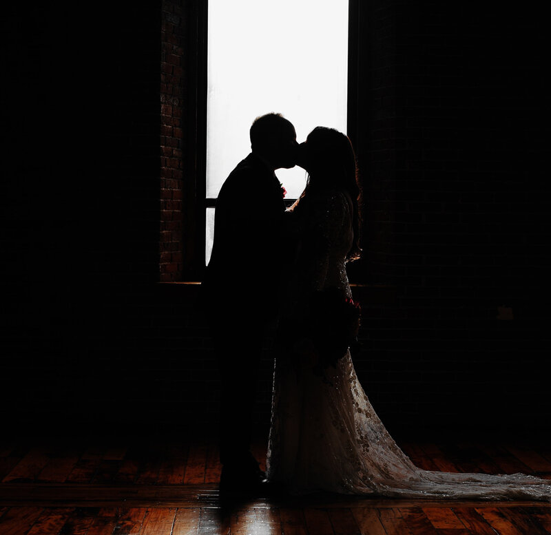 silhouette of a couple kissing in front of a window