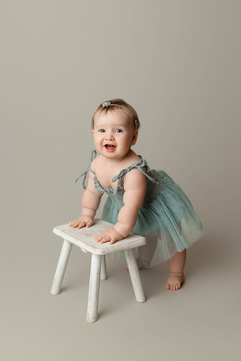 Newborn baby boy in a blue swaddle in a tan basket on a tan background