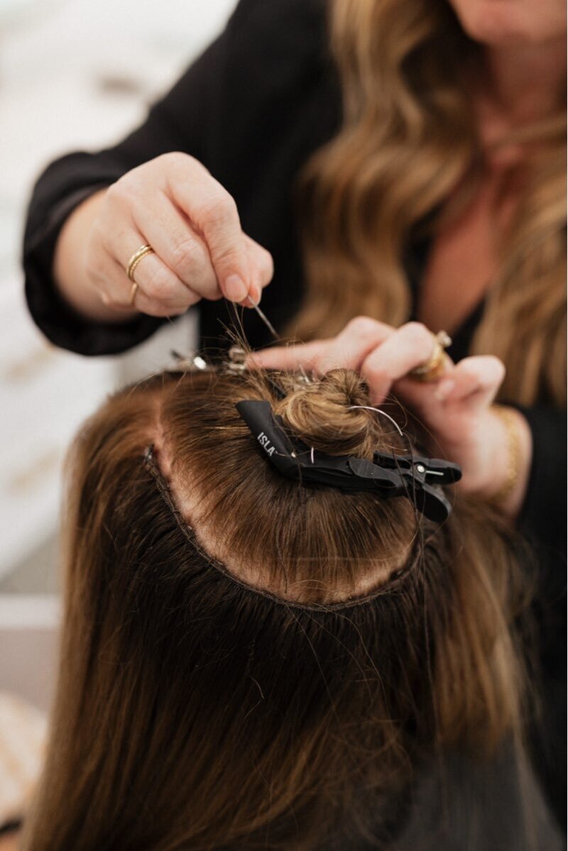 Hairstylist creating seamless and invisible hand tied hair extensions
