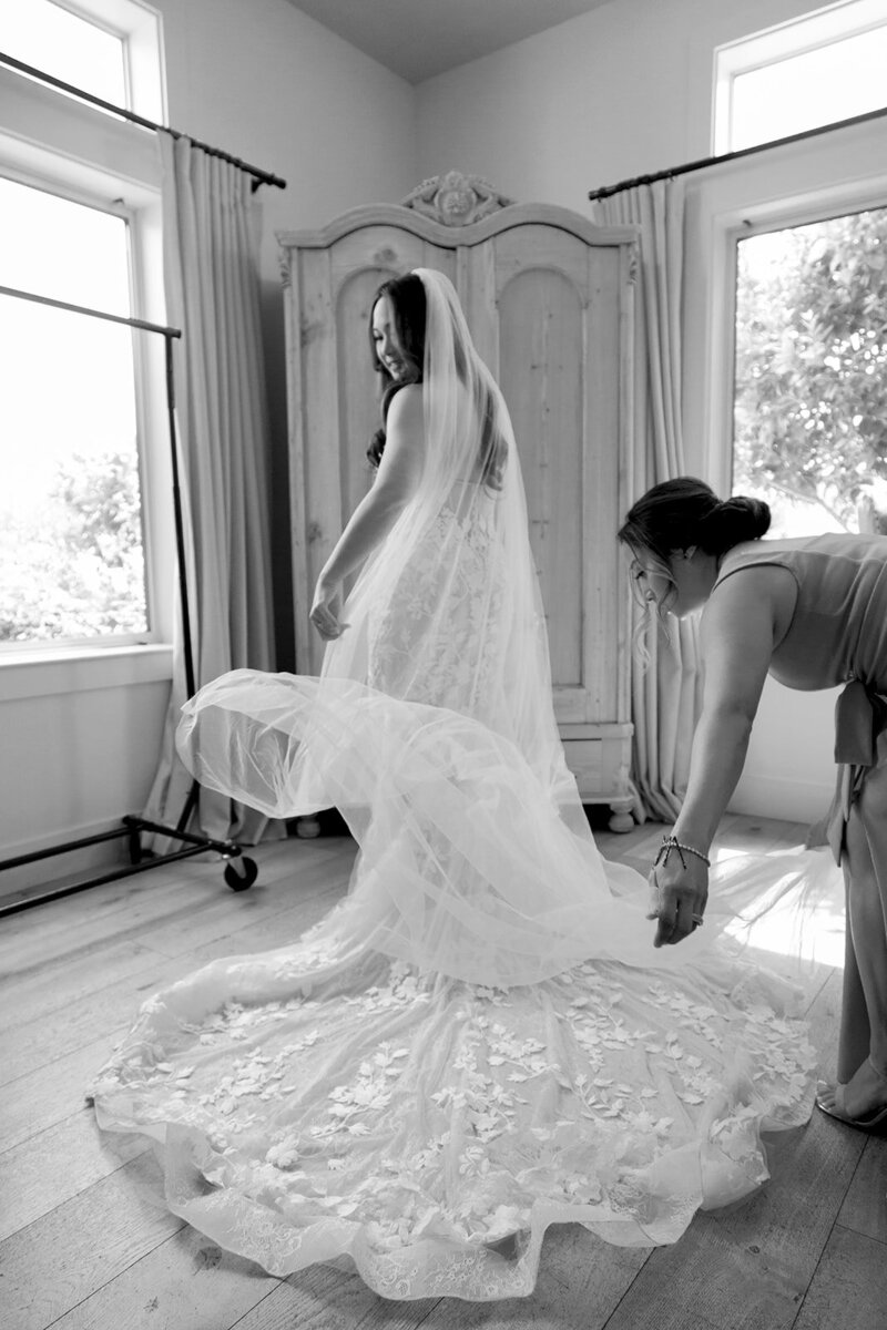 Bridesmaid helping bride with her wedding dress.