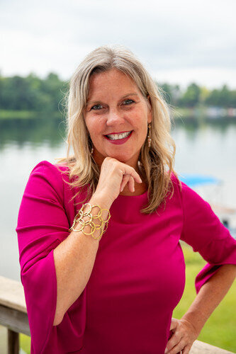 Jen Todd in a pink dress hand under chin