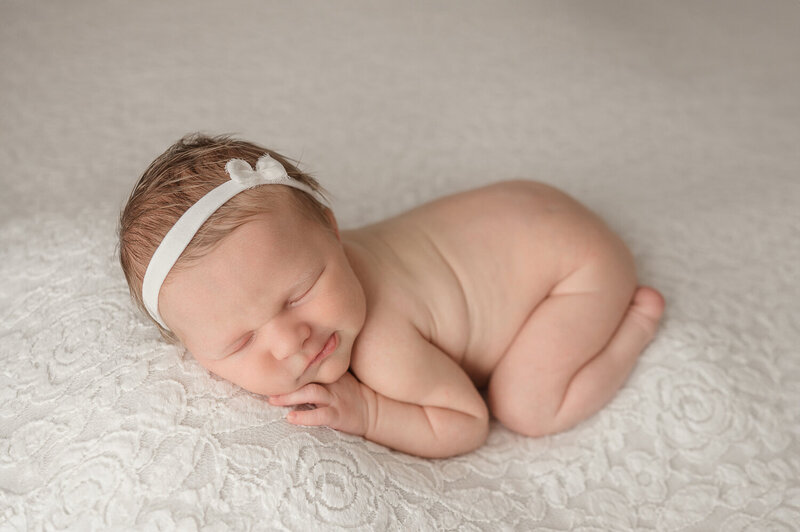 newborn baby on lace blanket with simple hair bow