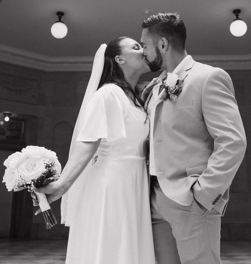 The groom and bride are kissing during the wedding ceremony.
