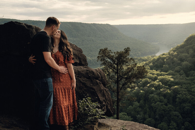 Couple kissing overlooking a river gorge at golden hour