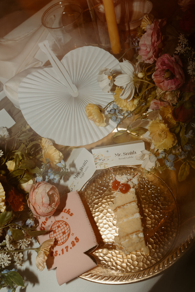 Photo of engagement and wedding rings in a pink velvet ring box on top of wedding invitations and other wedding details.