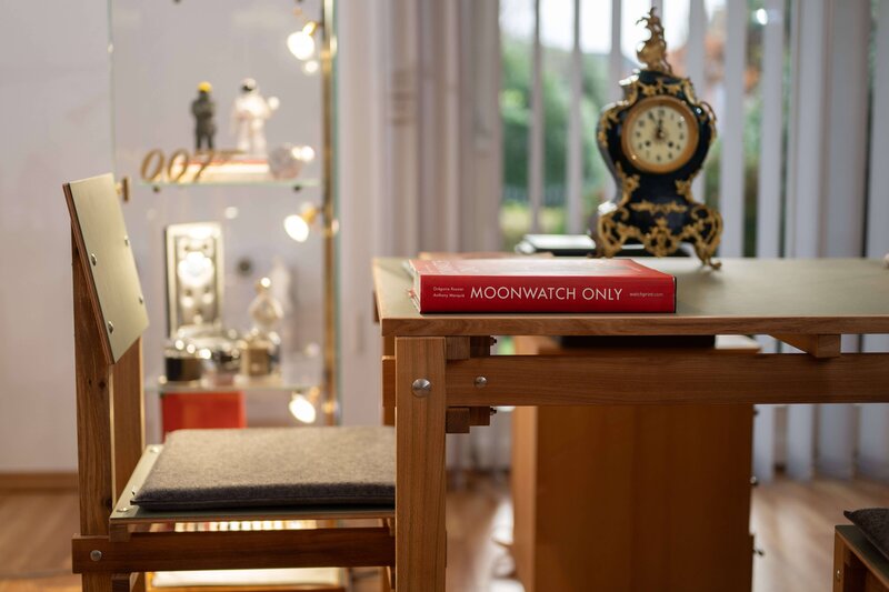 Empfangsraum bei Zur Horst Uhrenhandel mit einem eigens von Jürgen zur Horst angefertigten Tisch und Stuhl im Bauhaus-Stil. Auf dem Tisch liegt das rote Buch „Moonwatch Only“ über Omega, eine alte Tischuhr und im Hintergrund eine Vitrine mit exklusiven Ausstellungsstücken. Der Schriftzug „007“ und eine Raumfahrerfigur erinnern an die Omega-Uhren, die in den James-Bond-Filmen getragen wurden, sowie an die erste Omega-Uhr, die auf dem Mond war.