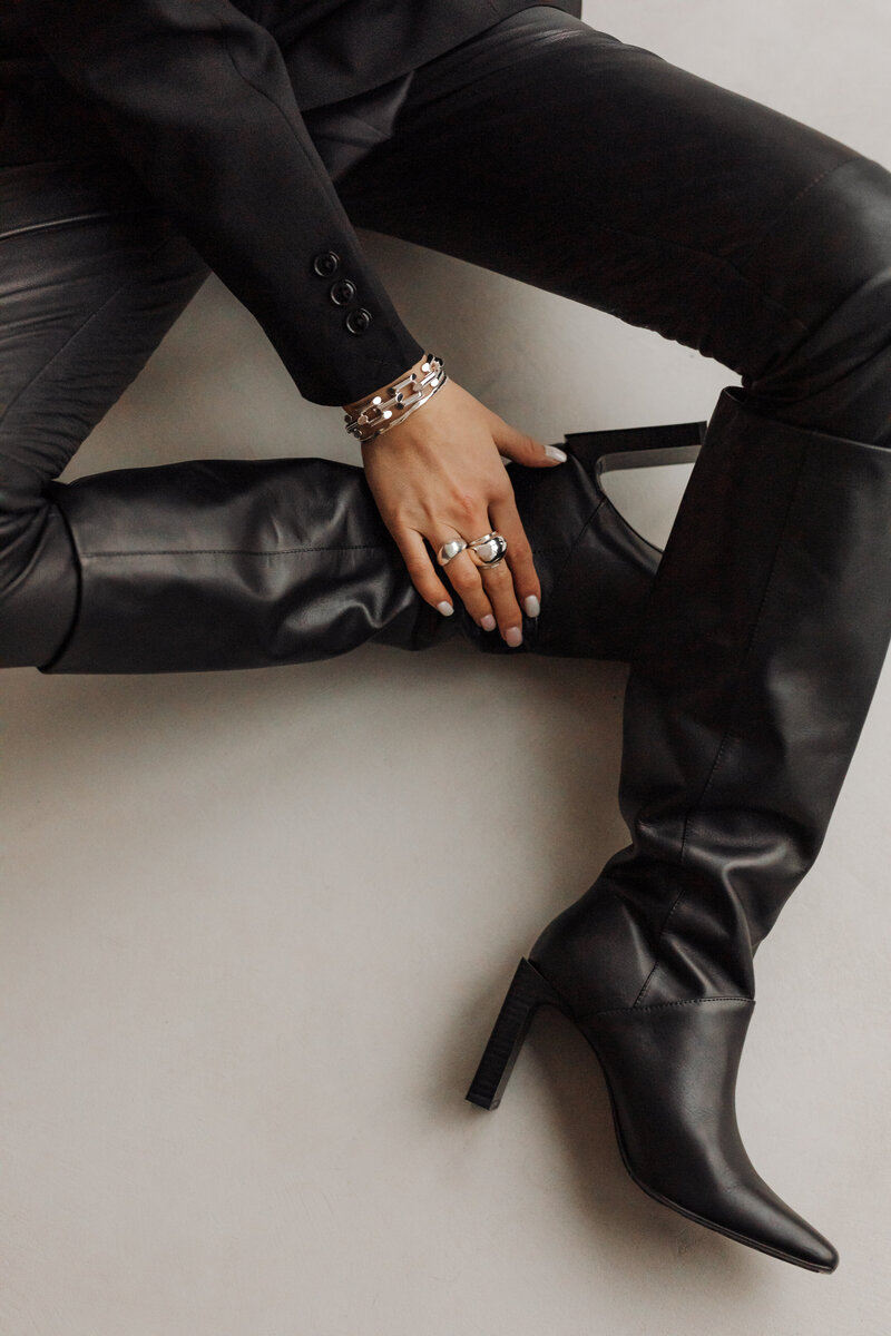 Woman in black wearing leather heels boots sitting on the floor