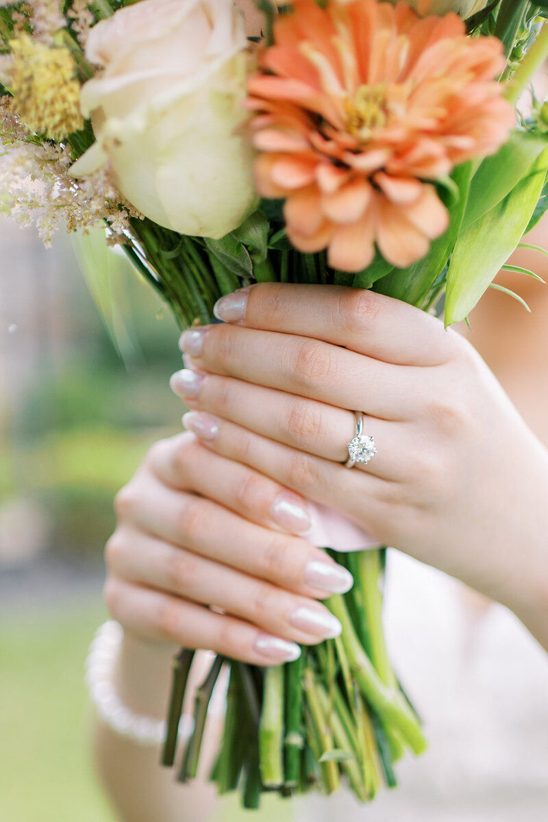 Hands wearing a diamond ring holding a bouquet of flowers