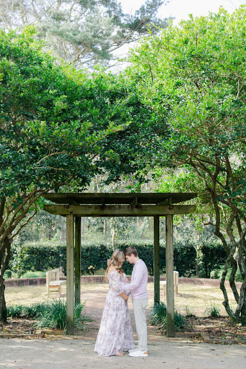 Woman and Man snuggling under arbor in a dothan alabama park during maternity photography session