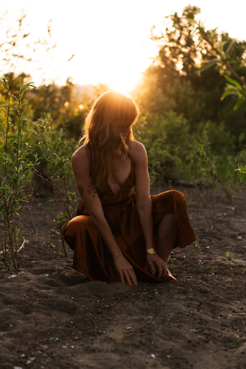 mentor, healer, guide sitting in a green field with a sunburst behind her