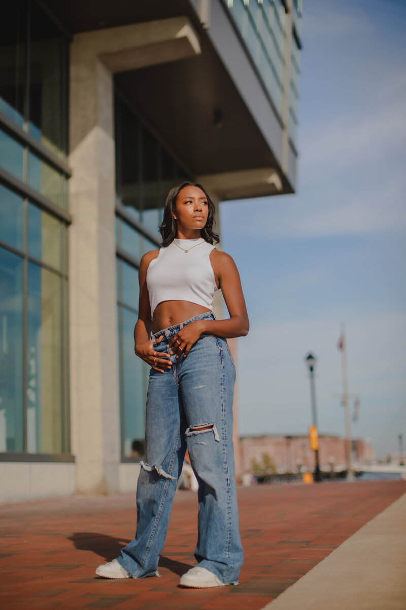 Beautiful african american teenager posing in basic outfit with jeans and white top in direct sunlight